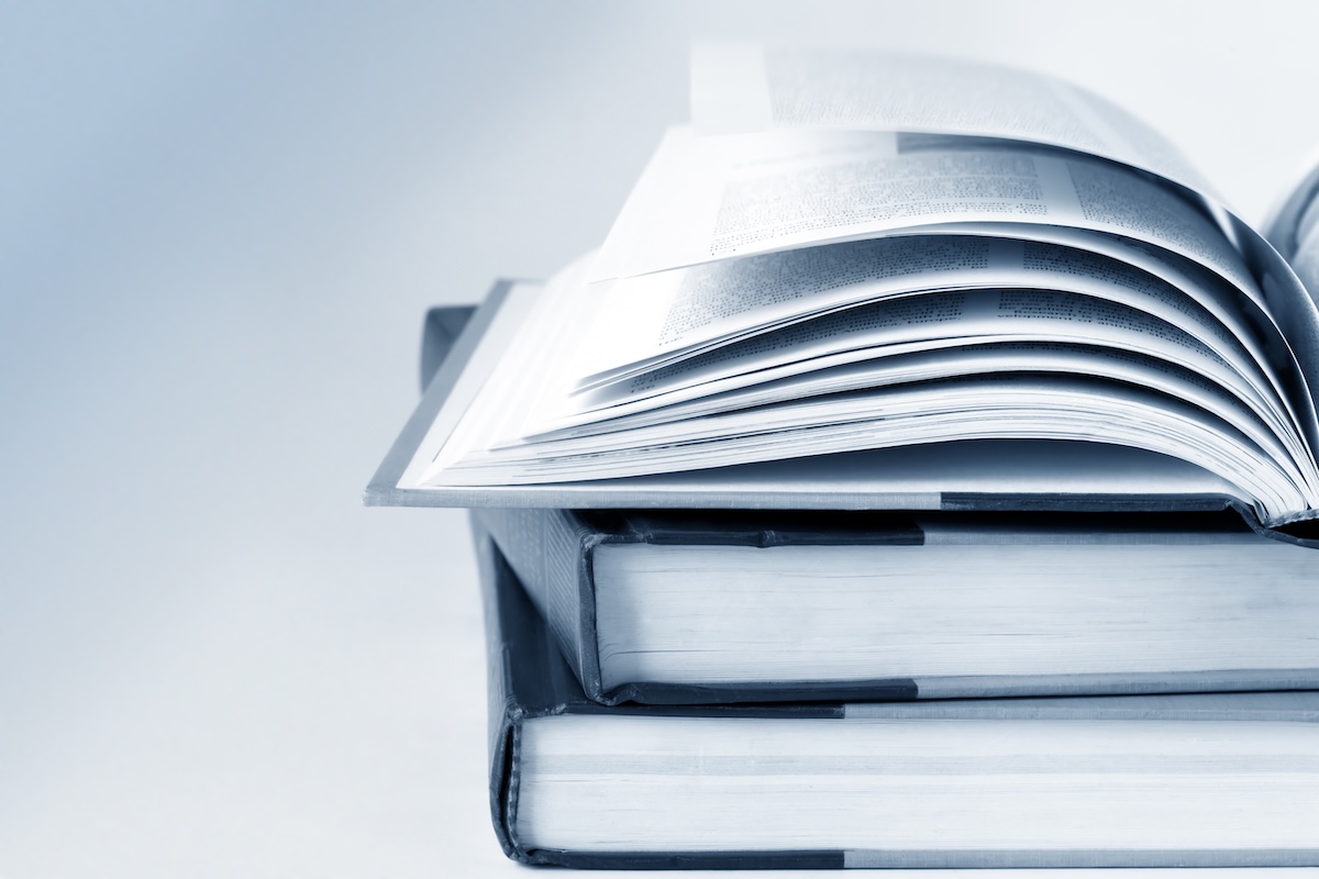 Image in black and white of an open book stacked on top of others. Used in a blog post